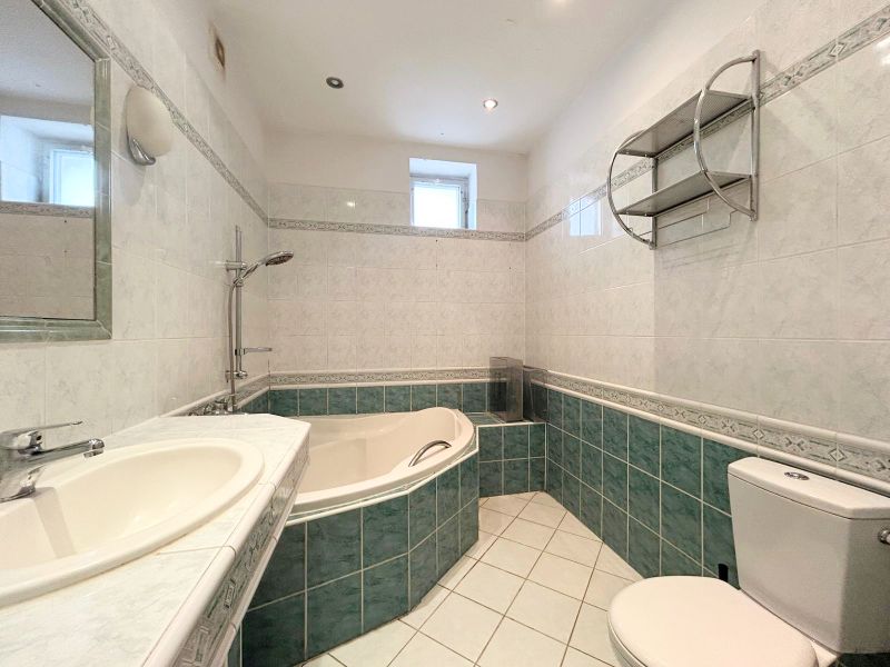 Fürdőszoba családi házban káddal, mosdóval, tükörrel és WC-vel.