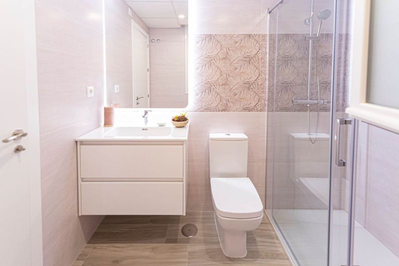 Fürdőszoba a nyaraló apartmanban fa mintázatú padlóval és zuhanyzóval.