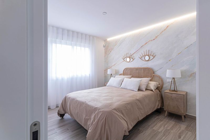 Hálószoba egy üdülő apartmanban ággyal, szövetfüggönyökkel és fa dekorációjú padlóval.