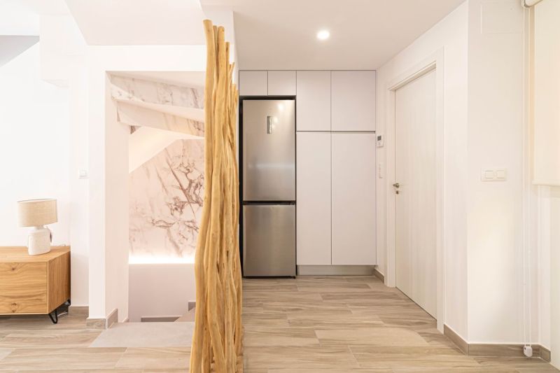 Nyaraló apartman belső tere konyhaszekrényekkel, hűtőszekrénnyel és fa dekorációjú padlóval.