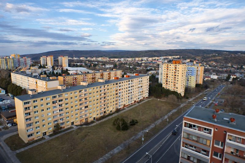 Kilátás a pozsonyi Dúbravka lakótelepre Janko Alexy utcából, zölddel és úttal körülvéve. Garzonlakás.