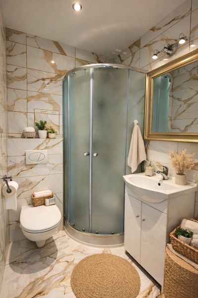 Fürdőszoba a garzonlakásban modern zuhanyzóval, WC-vel és dekorációkkal.