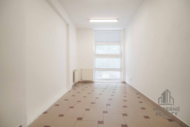 Iroda belső tér ablakkal és radiátorral, padló burkolva csempével.