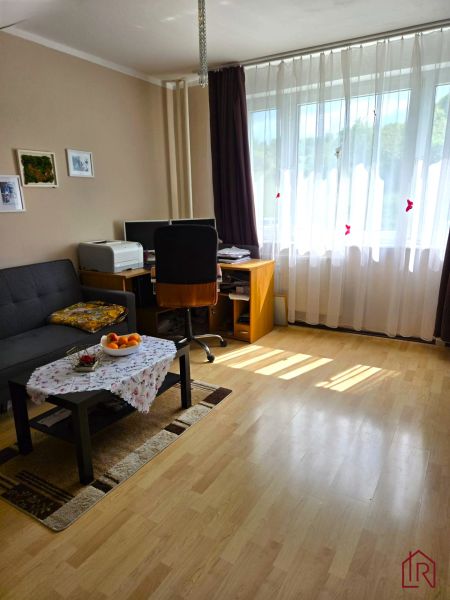Nappali egy négy szobás lakásban fa dekorációjú padlóval és dolgozósarokkal.