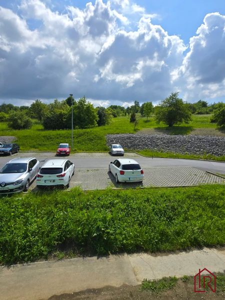 Parkoló autókkal a Ďumbierska utcán, Eperjesen, zölddel és éggel körülvéve.