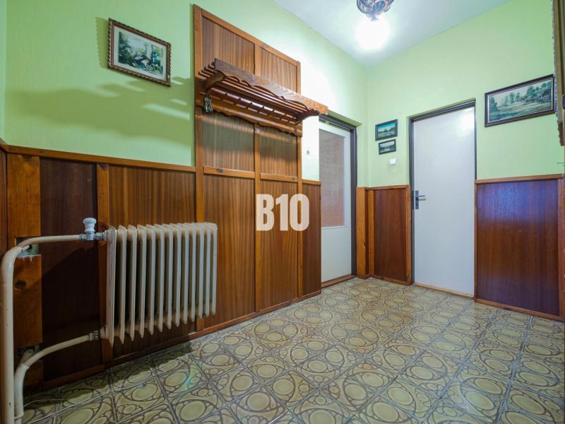 Családi ház előszobája fa burkolattal és vintage radiátorral.