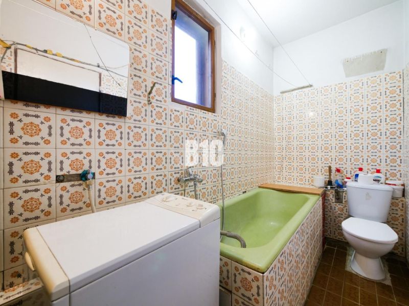Fürdőszoba retro csempével és zöld káddal egy családi házban.