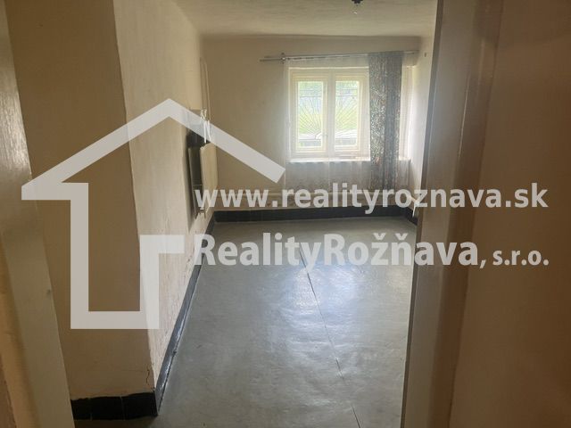 Szoba egy családi házban betonpadlóval és bejövő fényt árasztó ablakkal.
