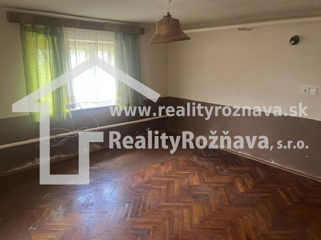 Szoba egy családi házban fa dekorációjú padlóval és zöld függönyökkel.