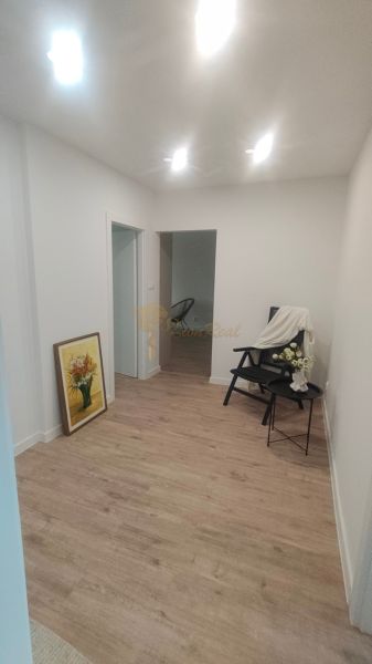 4 szobás lakás belső tere fa dekoros padlóval, székkel és festménnyel.