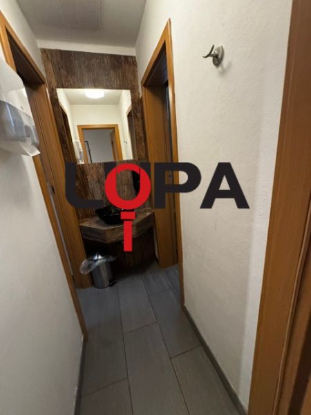 Az üzlethelyiségek folyosója sötét padlóval és fehér falakkal.