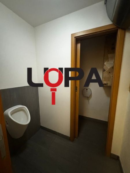 Üzlethelyiség belső tér WC-vel és sötét, fa dekoros padlóval.