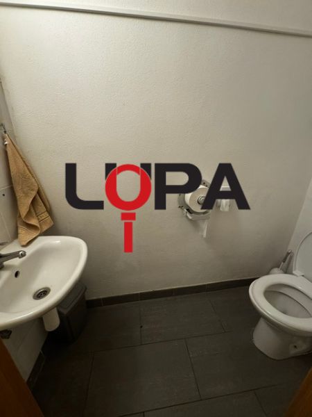 Mosdó mosdókagylóval és csempével. Üzlethelyiség egyszerű berendezéssel.