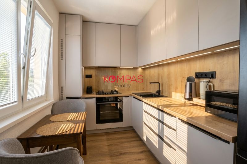 Konyha egy kétszobás lakásban fa dekorációjú szekrényekkel és kompakt asztallal.