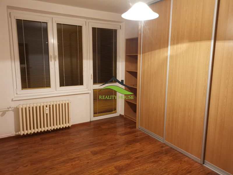 Szoba fa dekor padlóval és nagy beépített szekrénnyel egy háromszobás lakásban.