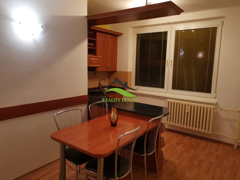 Konyha egy háromszobás lakásban, fa dekor padlóval és étkezőasztallal.