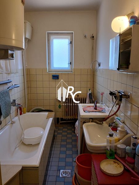Családi ház fürdőszobája káddal, mosdóval és mosógéppel, csempékkel körülvéve.