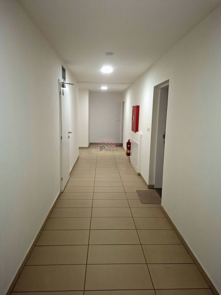 Folyosó fehér falakkal, csempével és vészhelyzeti felszereléssel egy garzonlakásban.
