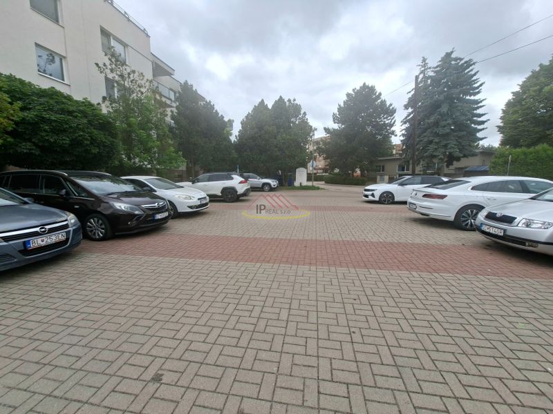 A Dunaszerdahelyi Sport utcában, az épület előtti parkoló autókkal.