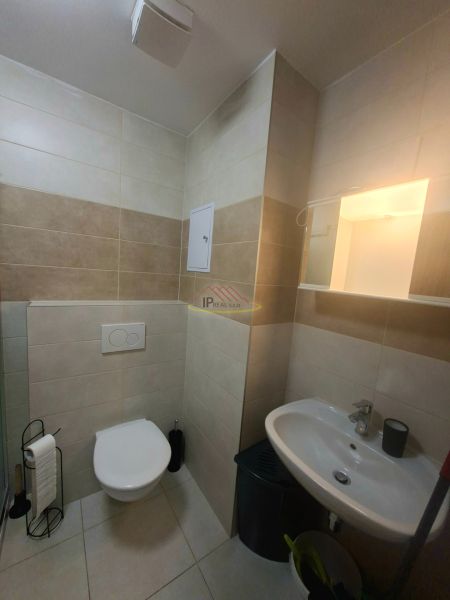 Fürdőszoba a garzonlakásban mosdóval, WC-vel és csempézett falakkal.