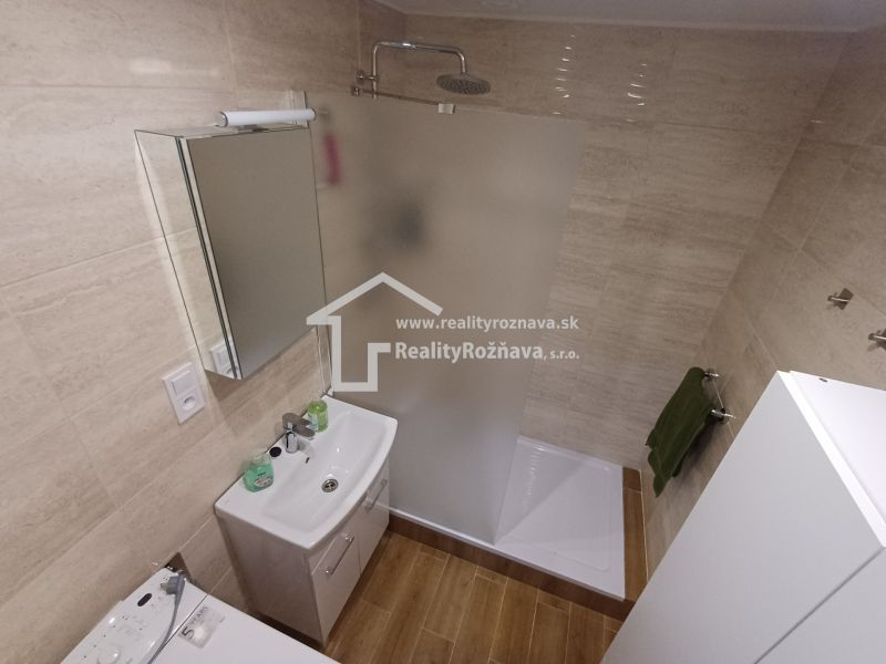 Fürdőszoba egy háromszobás lakásban WC-vel, zuhanyzóval és fa mintázatú padlóval.