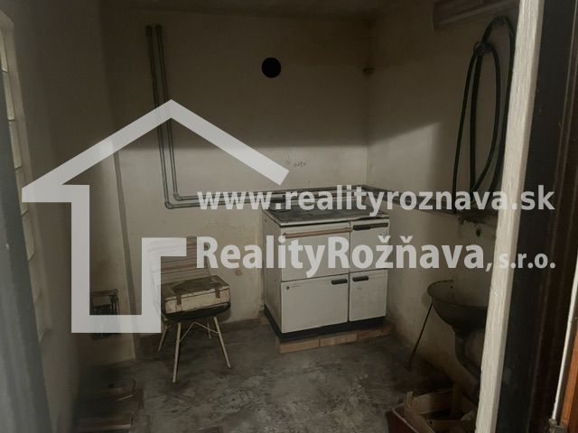Kis szoba konyhai tűzhellyel, mosogatóval és betonpadlóval, alkalmas nyaralóhoz.