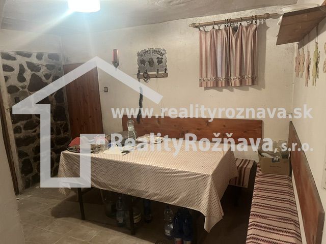 Étkező sarok terítővel, paddal és kőfallal a házikóban.