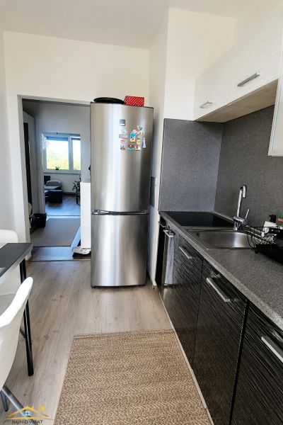 Konyha egy kétszobás lakásban hűtőszekrénnyel és fa mintázatú padlóval.