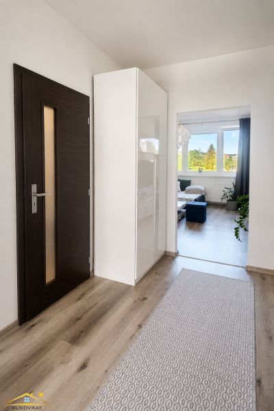 Kétszobás lakás folyosója fa dekoros padlóval, amely a nappaliba vezet.