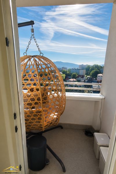 Erkély egy 2 szobás lakásban rattan székkel és kilátással a városra.