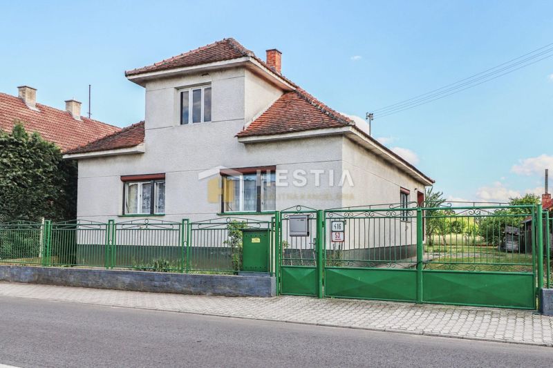 Családi ház Borsky Mikulášban fehér falakkal és zöld kerítéssel.