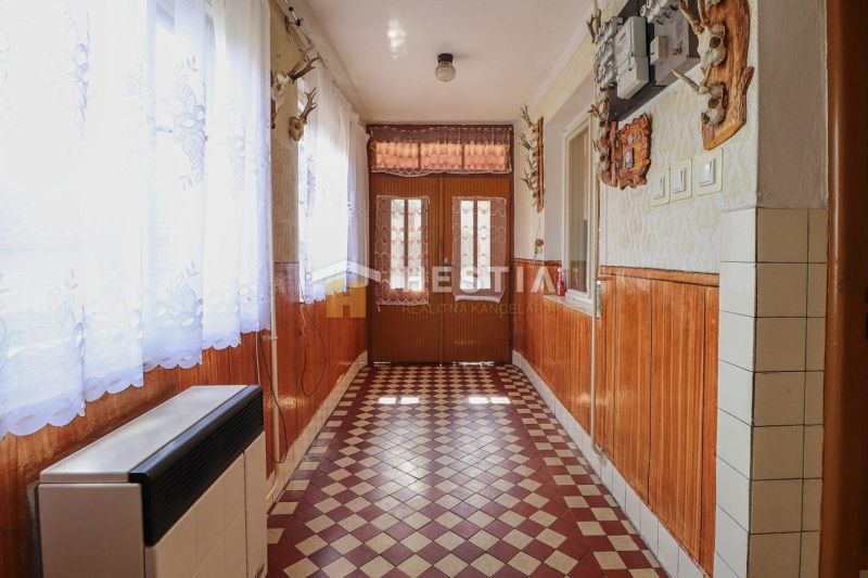 Folyosó egy családi házban csempézett padlóval és fa falburkolattal.