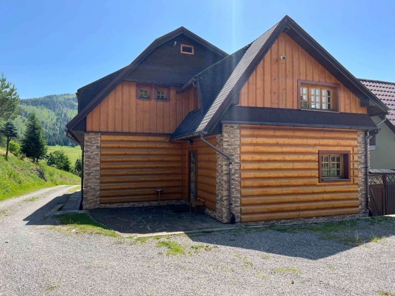 Családi ház Nagyborovón, fával és kővel burkolt külsővel, az erdő mellett.