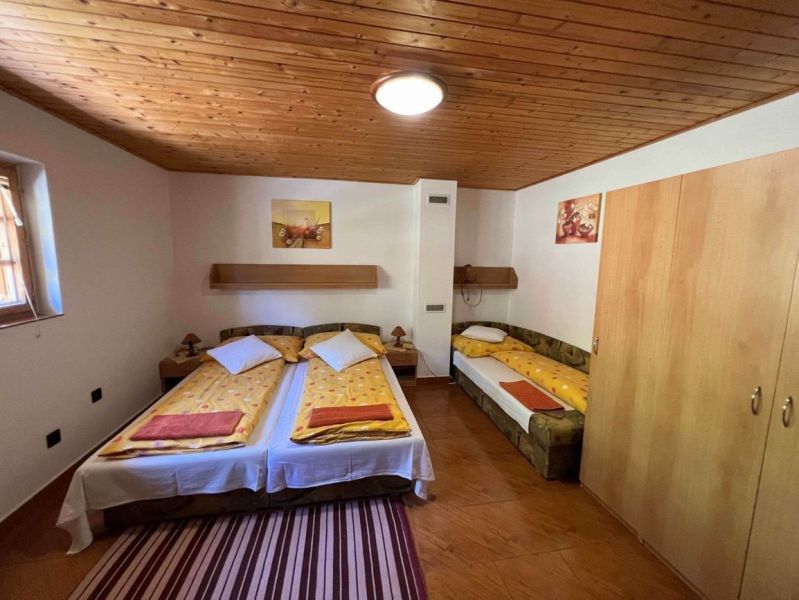 Hálószoba fa mennyezettel, három ággyal és fa dekorációjú padlóval egy családi házban.