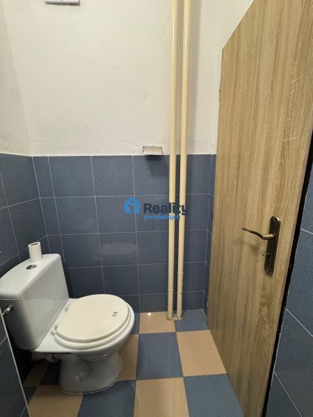 Kék csempés WC a kétszobás lakásban, fa dekoros ajtókkal.