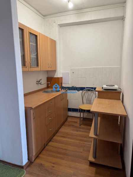 Kompakt konyha egy kétszobás lakásban világos bútorokkal és fa dekorációjú padlóval.