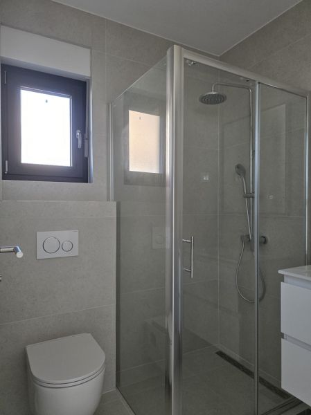 Fürdőszoba üveg zuhanykabinnal és WC-vel egy 4 szobás lakásban.