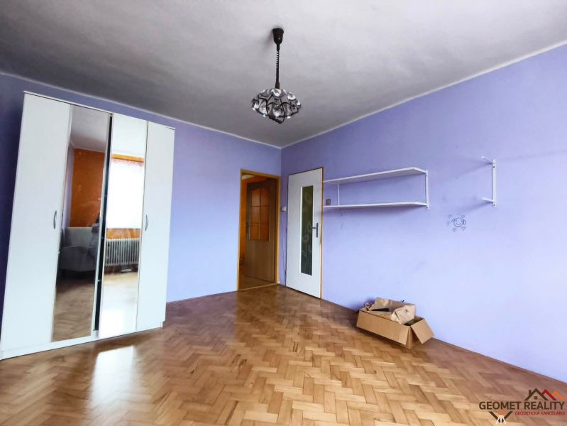 Lila szoba fehér szekrénnyel és fa dekorációjú padlóval egy háromszobás lakásban.