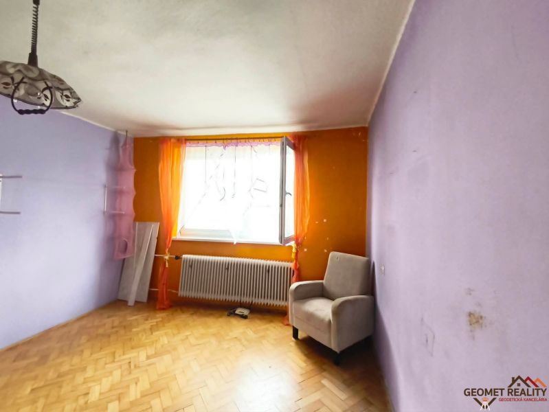 Szoba egy háromszobás lakásban levendulaszínű falakkal és fa dekorációjú padlóval.