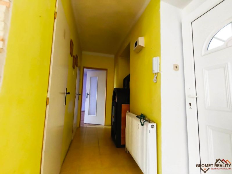 Folyosó fehér ajtókkal és sárga falakkal egy háromszobás lakásban.