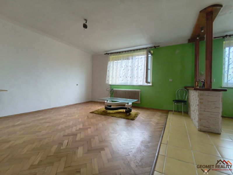 Nappali szoba fa mintázatú padlóval és zöld fallal egy háromszobás lakásban.