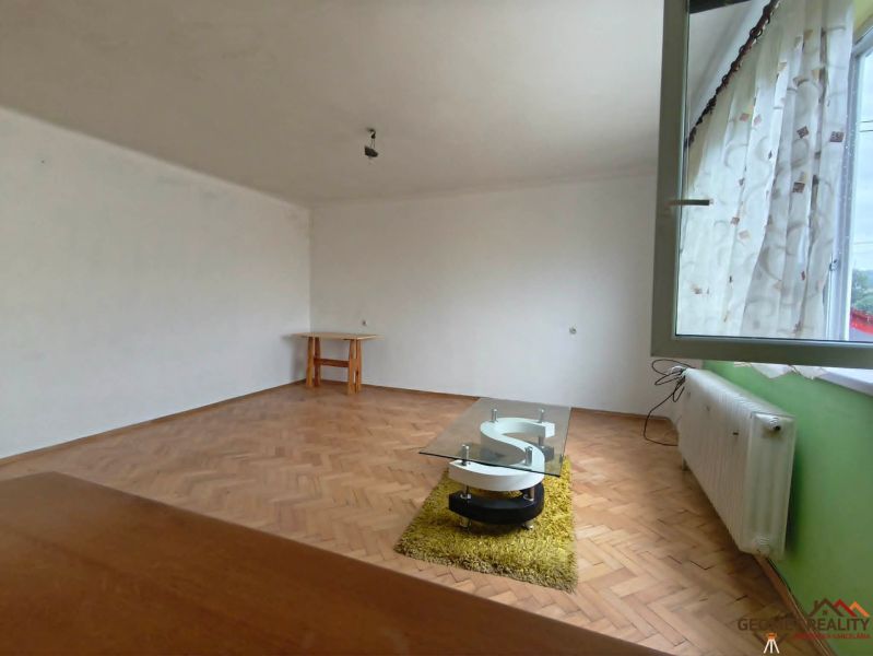 Nappali egy háromszobás lakásban, fa dekorációjú padlóval és bútorokkal.