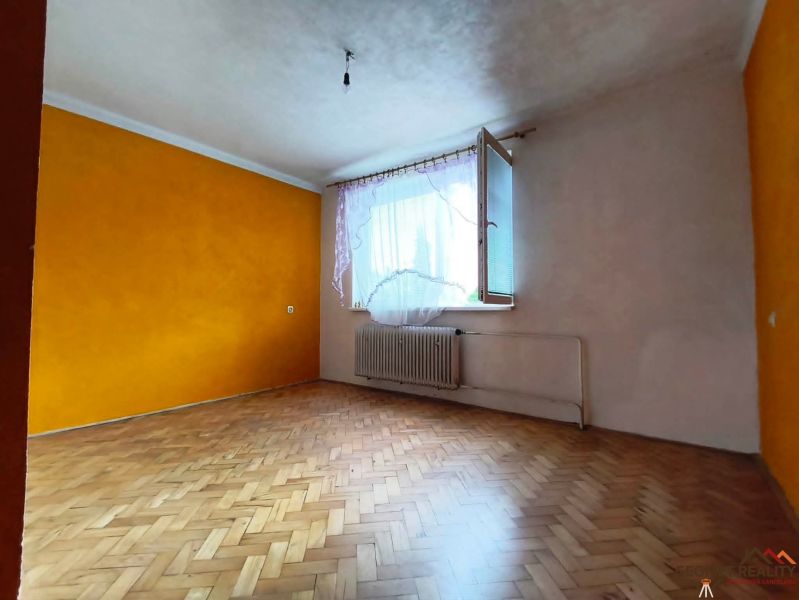 Szoba egy háromszobás lakásban narancssárga fallal és fa dekorációjú padlóval.