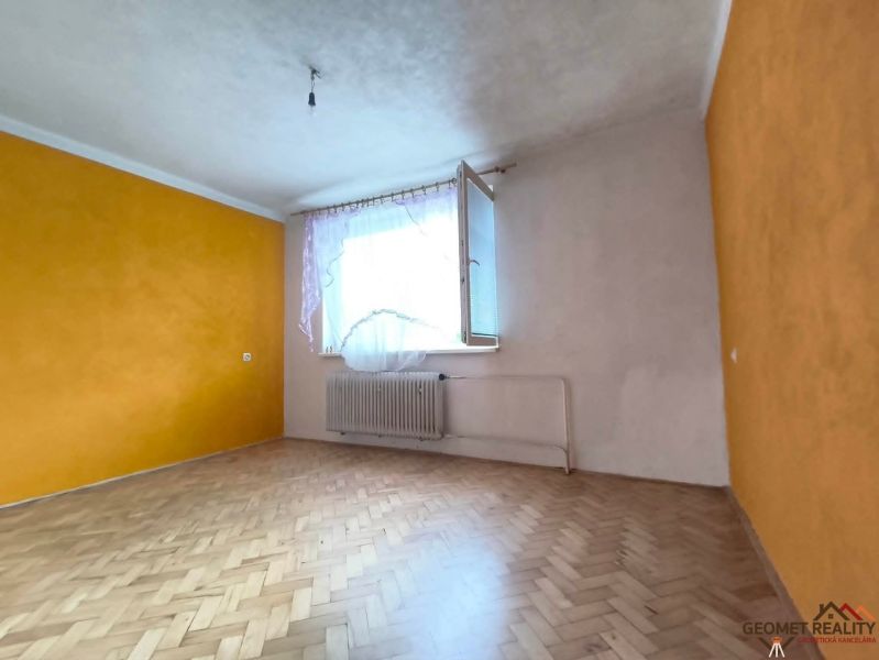 Tágas szoba egy háromszobás lakásban, fa dekoros padlóval.