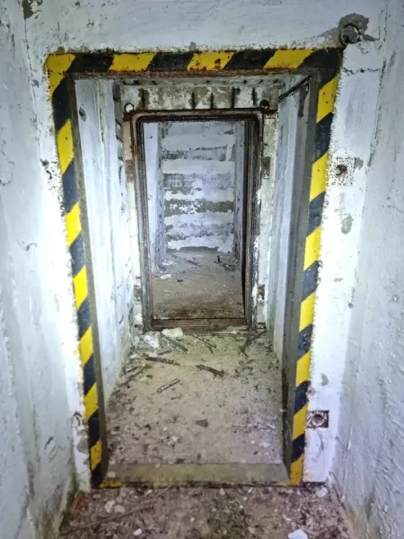 Elhagyatott belső tér egy különös ingatlanban betonfalakkal és poros padlóval.