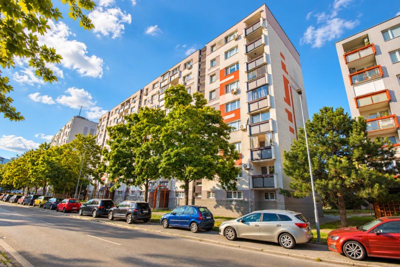 Tömbház a pozsonyi Ružinov városrészben, a Hraničná utcában, autókkal körülvéve.