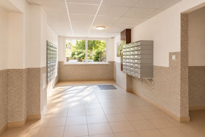 Világos folyosó postaládákkal és ablakkal.