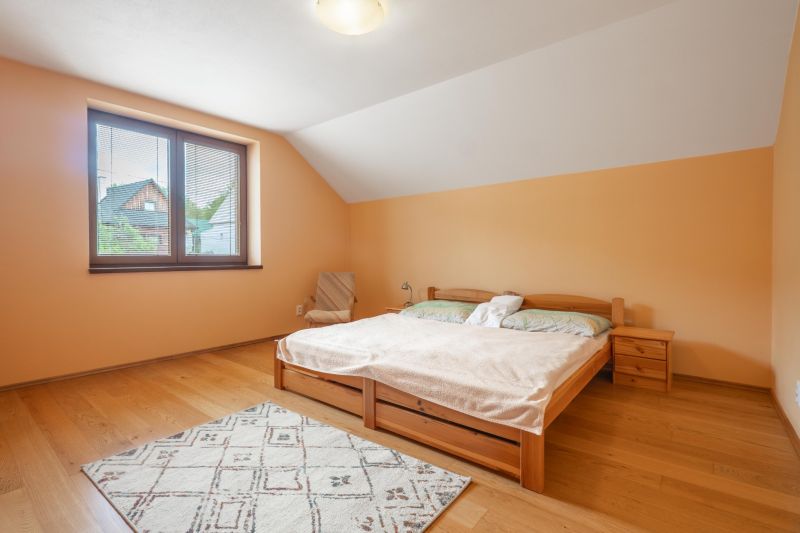 Hálószoba fa dekor padlóval egy családi házban, világos bútorokkal és kilátással rendelkező ablakkal.
