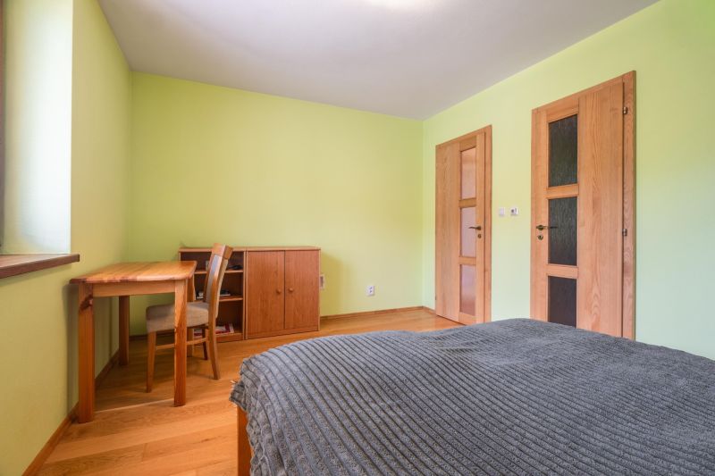 Hálószoba családi házban fa bútorokkal és fa dekoros padlóval.