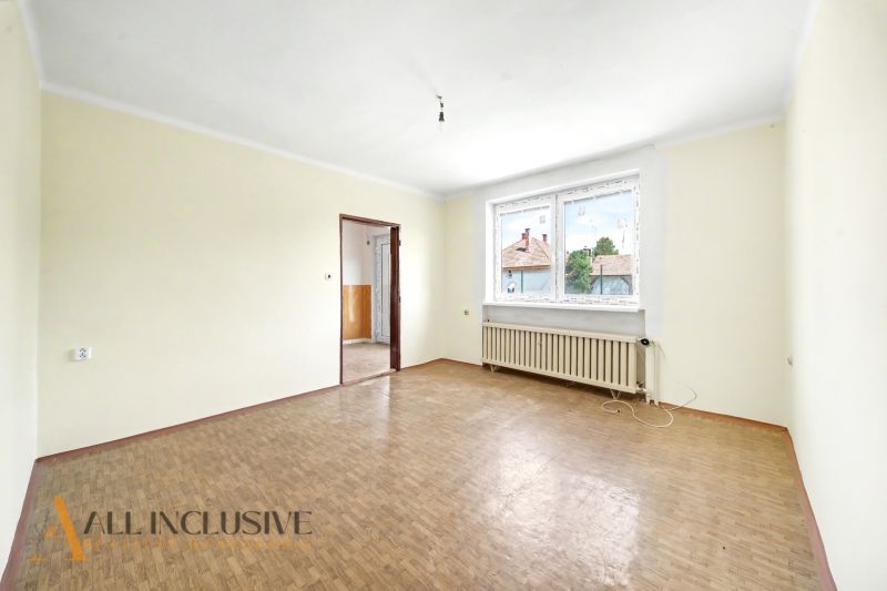 Tágas szoba fa mintázatú padlóval és nagy ablakkal egy családi házban.